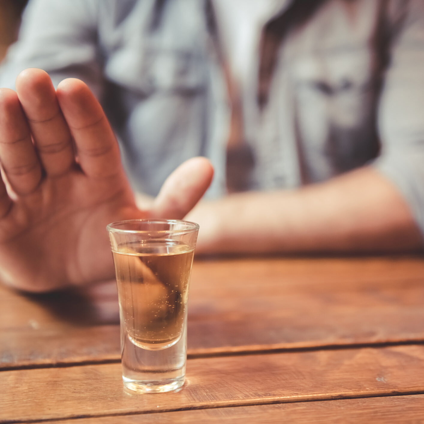 Cropped image of man showing stop gesture and refusing to drink